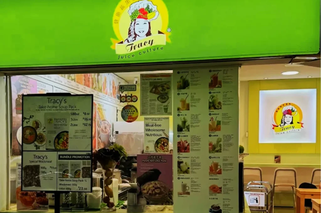 Storefront of "Tracy Juice Culture" with a bright green sign. Menu boards display juice and meal options. Interior appears inviting and wholesome.