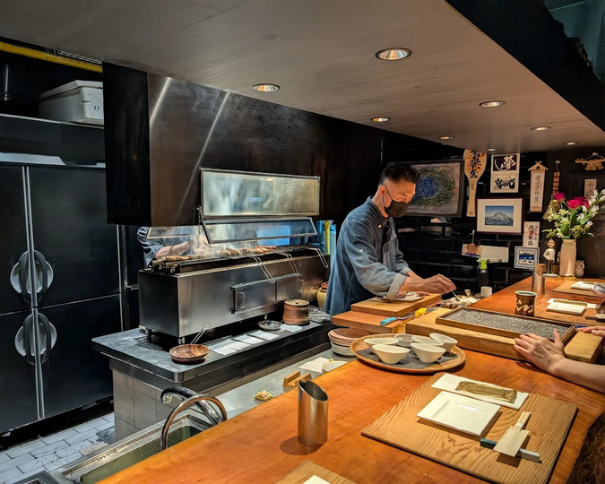 Cuppage Plaza Food : The warm glow of an izakaya interior with diners enjoying freshly grilled skewers