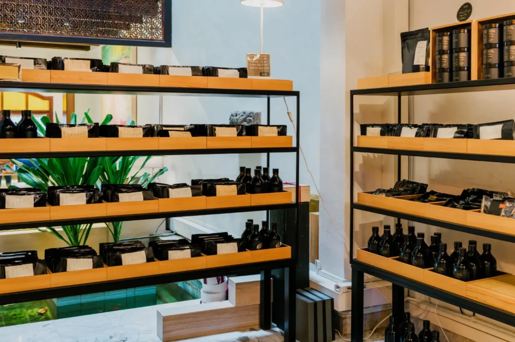 Wooden shelves in a brightly lit store display various black bottles and packages, creating a modern and organized retail space with a cozy ambiance.