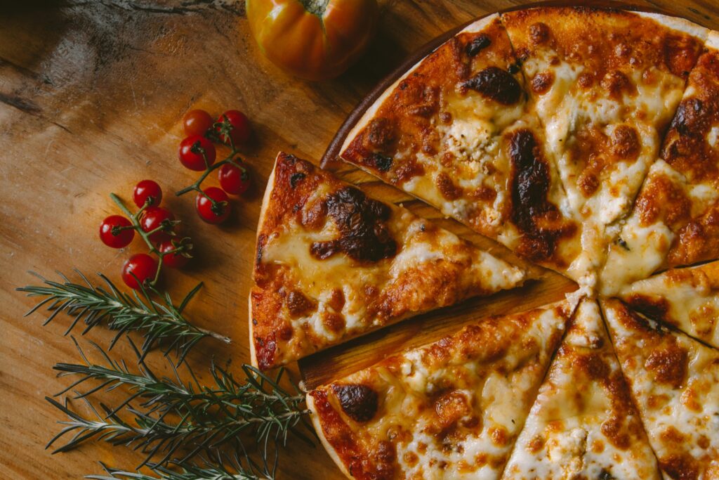 Beyond the Orchard Road : A cosy café setting with a hot pizza on the table and warm ambient lighting.