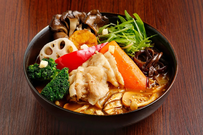 Sapporo Soup Curry in SG : A beautifully presented bowl of Hokkaido soup curry on a wooden table, the rich aroma of spices rising from the broth—an authentic taste of Sapporo’s culinary soul.