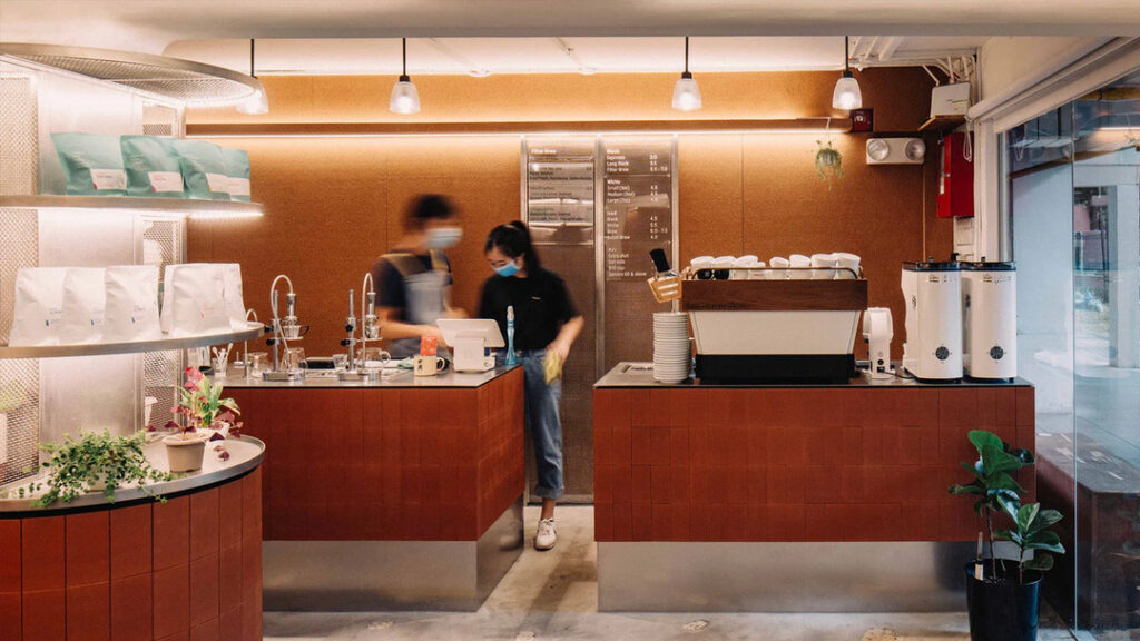 Best Coffee in SG : A barista at Nylon Coffee Roasters carefully brewing pour-over coffee behind the small wooden counter, showcasing the craftsmanship and precision that define this beloved hole-in-the-wall spot.