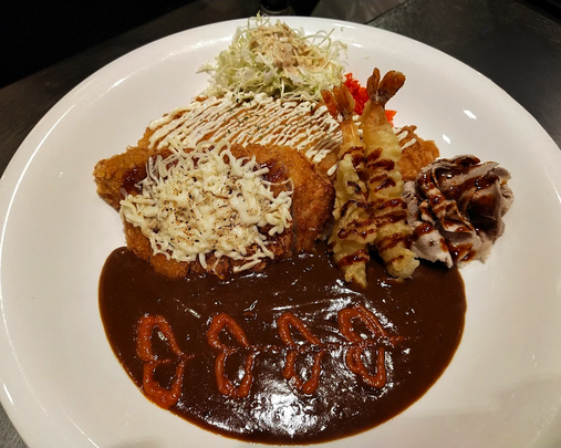 A massive Monster Combo Curry, featuring a variety of proteins such as chicken katsu, pork cutlet, and seafood, served over generous portions of fluffy rice and topped with rich curry sauce. This satisfying meal highlights the best Japanese curry rice experience, perfect for those seeking a hearty and flavorful dish.