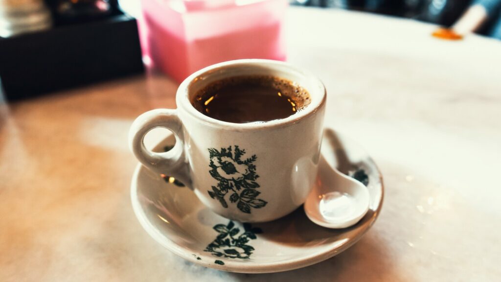 A cup of traditional Kopi coffee, rich and dark, served authentically in a local cafe setting, representing Singapore’s classic coffee culture.