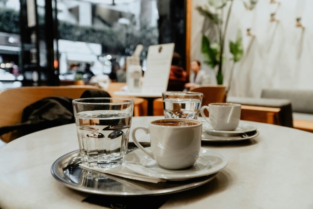 An angle of a cup of coffee resting on a café table, capturing a calm moment with a simple and cosy ambience