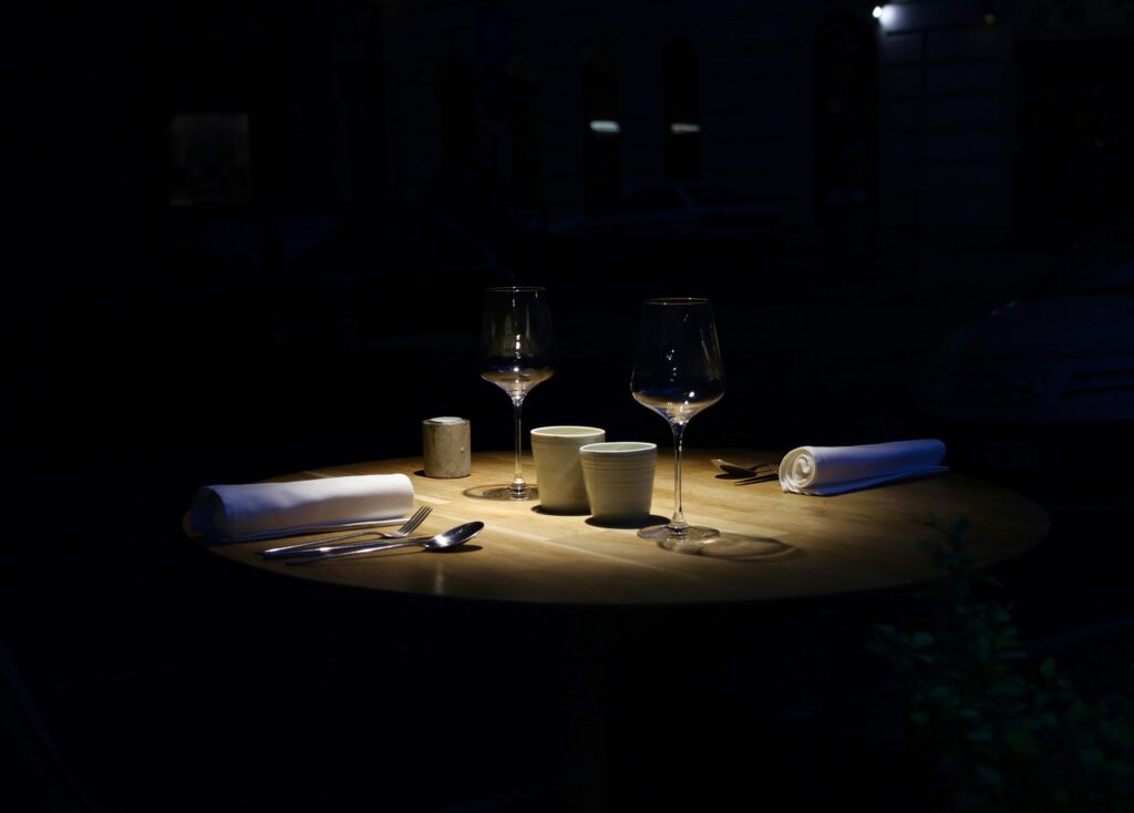 The image depicts an intimate restaurant dining room featuring candlelit tables adorned with wine glasses, all set against stunning views of the city skyline. This cozy trattoria offers authentic Italian cuisine, including handmade pastas and wood-fired pizzas, making it one of the best Italian restaurants in Singapore's dining scene.