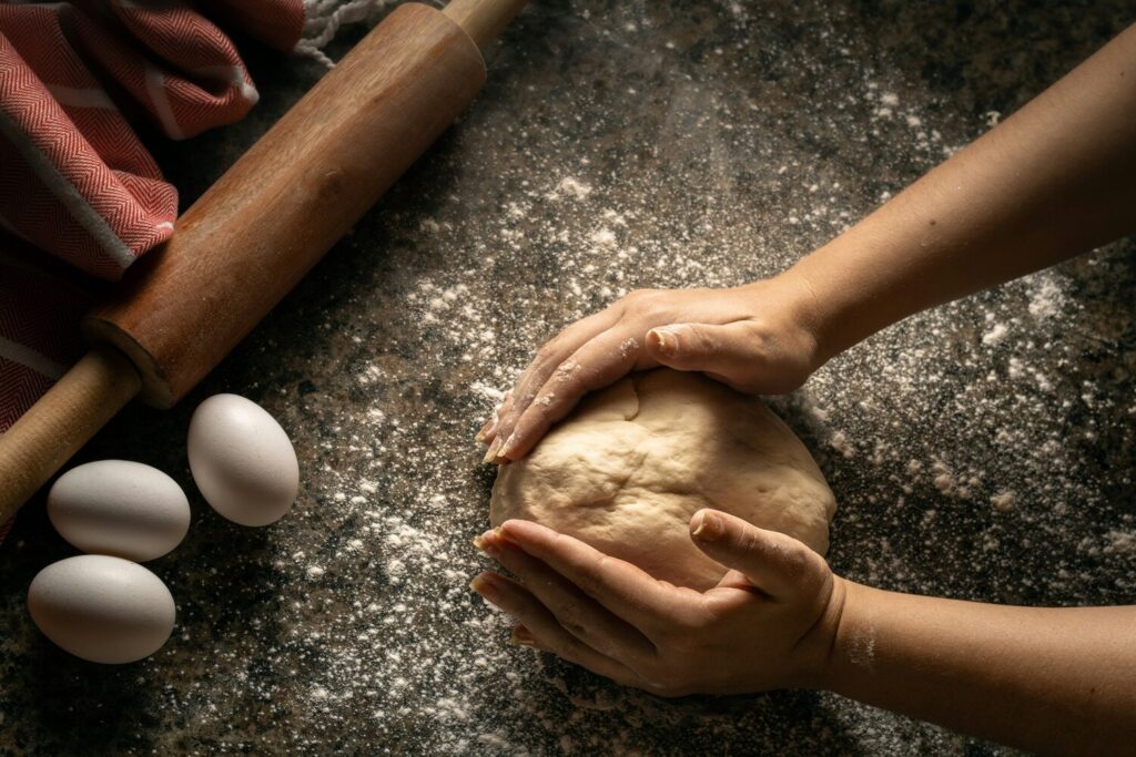 A close-up shot captures artisanal pizza dough being hand-stretched, revealing its airy, bubbled texture that showcases the quality and tradition of pizza making. This image highlights the craftsmanship of pizza makers, perfect for those craving a fresh slice from a pizzeria like l'Antica Pizzeria da Michele in Singapore.