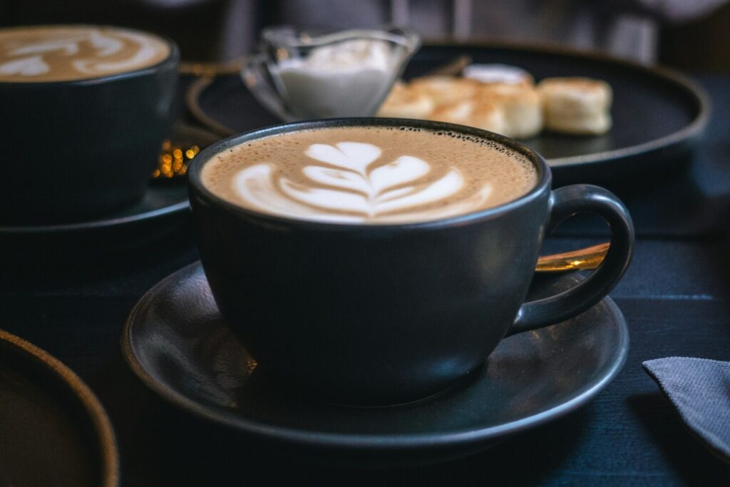 A visually stunning cup of coffee with intricate latte art, presented on a saucer with a warm and inviting cafe ambiance in the background.