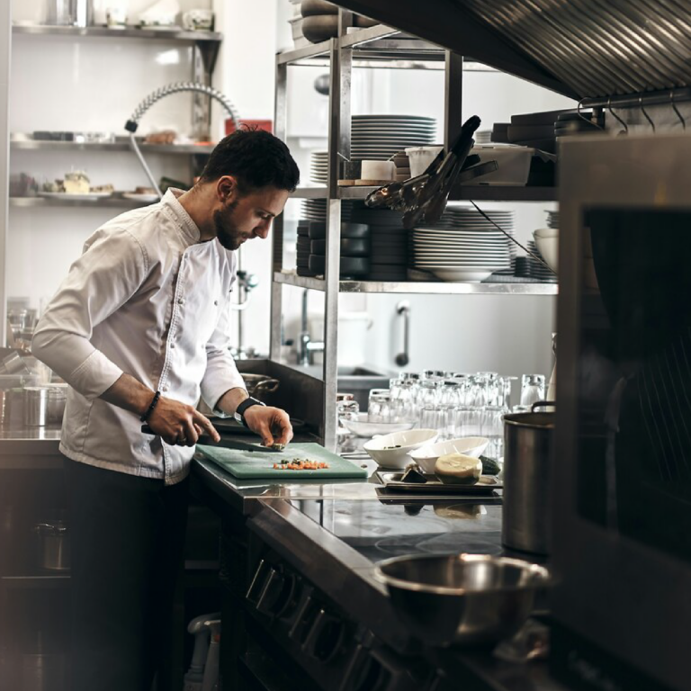 A chef actively cooking in a restaurant kitchen, focused and immersed in the process of preparing a carefully crafted meal.
