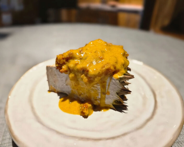 A signature creation featuring smoky durian. The dish showcases a harmonious contrast of bold aromas, vibrant flavours, and rustic elegance on a refined plate.