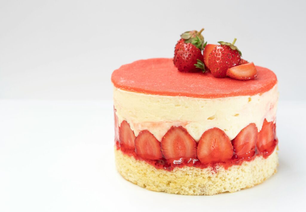 A light and fluffy strawberry shortcake layered with fresh cream and sliced strawberries, topped with a glossy whole berry for a sweet, elegant finish