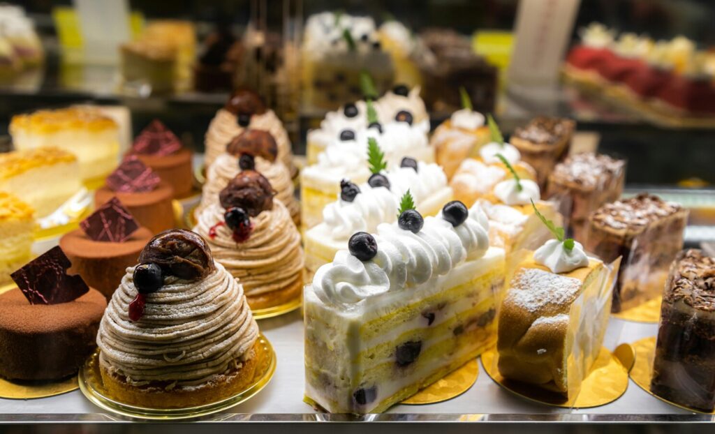 A glass display filled with freshly baked pastries, showcasing flaky croissants and golden tarts arranged neatly inside a chic modern café