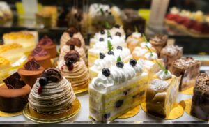 A glass display filled with freshly baked pastries, showcasing flaky croissants and golden tarts arranged neatly inside a chic modern café