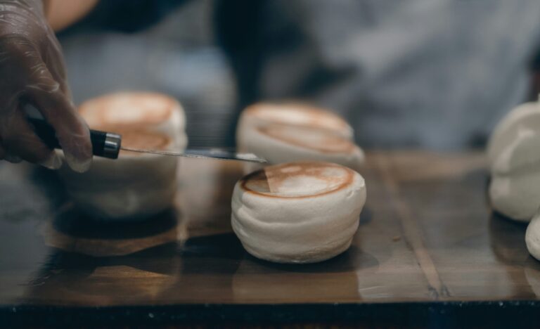 A perfectly risen soufflé dusted with icing sugar, served warm in a porcelain ramekin, highlighting its airy texture and golden top