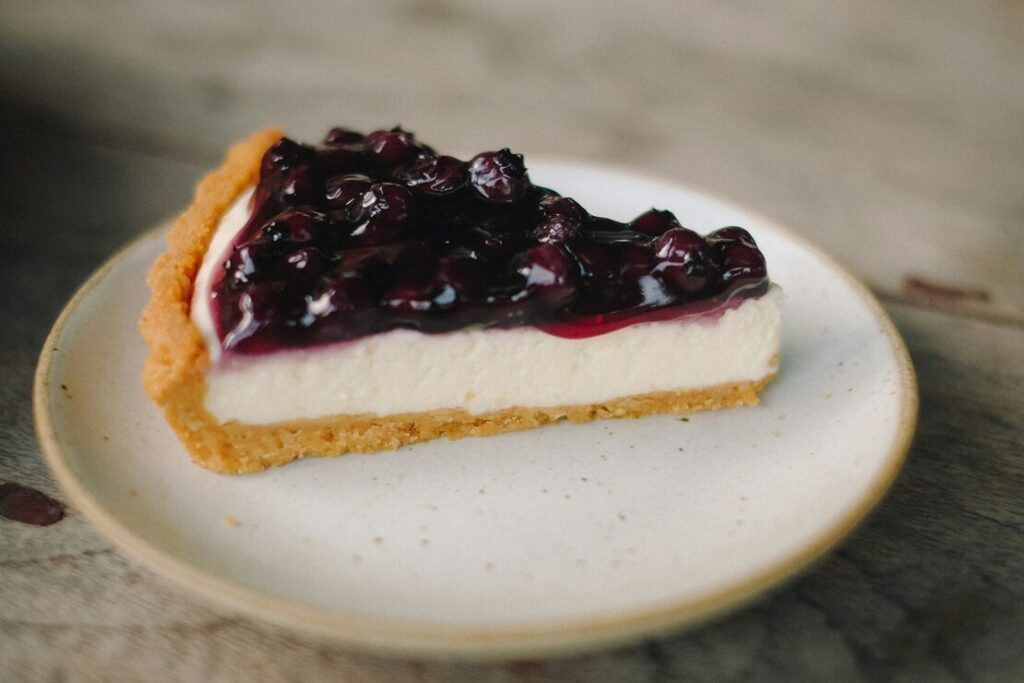 A creamy blueberry cheesecake layered with fresh blueberry compote, offering a rich tanginess and buttery biscuit base.