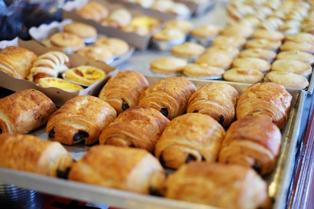 An assortment of fresh pastries displayed on a counter, showcasing flaky layers and buttery aroma, ideal for a morning treat or café indulgence