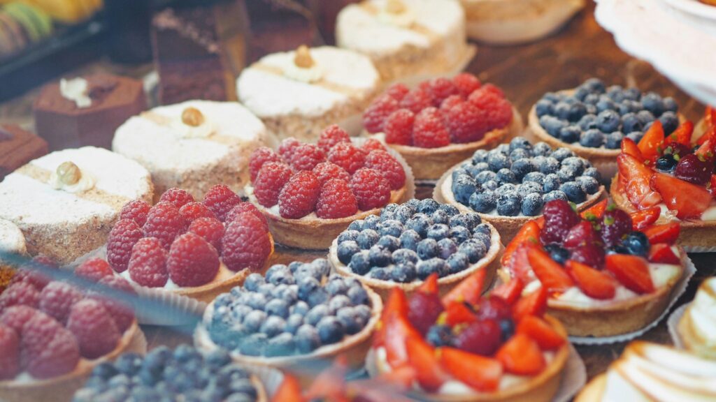 An assortment of freshly baked pastries displayed in a café, including croissants and tarts, arranged neatly on a wooden counter for a tempting showcase.