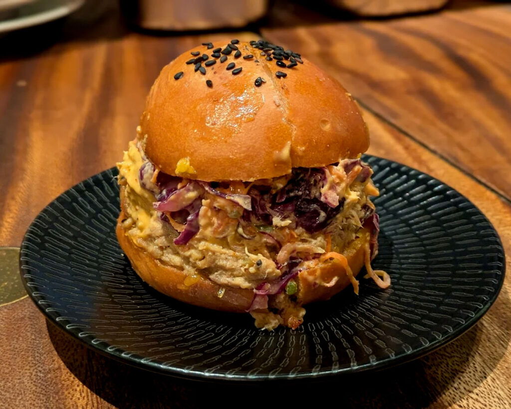 A gourmet burger served on a plate at Burnt Ends Restaurant, featuring a juicy patty, lightly toasted bun, and carefully selected accompaniments that reflect bold, well-crafted flavours.