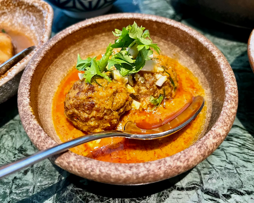 A beautifully presented bowl of Candlenut’s signature curry chicken, simmered in a rich, aromatic coconut gravy with tender chicken pieces, showcasing the depth of Peranakan flavours.