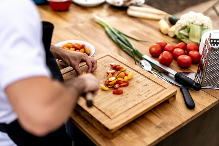 The chef’s hands finely slice fresh vegetables, highlighting the importance of knife skill, balance, and preparation in refined cuisine.