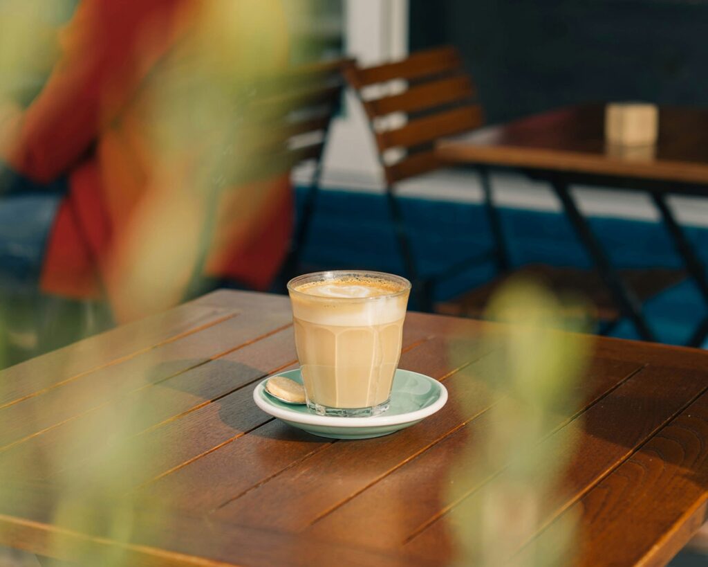 Glass of freshly brewed coffee placed on a café table, with soft background blur and warm ambient lighting.