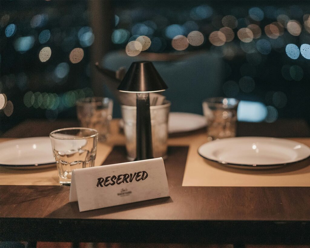 A simple “Reserved” sign placed neatly on a dining table, indicating a thoughtfully prepared space for an upcoming guest in a serene restaurant setting.