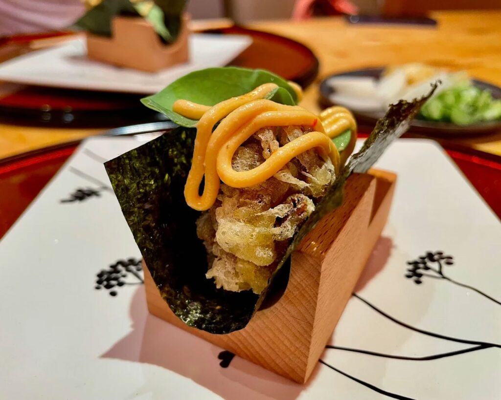 A hand-rolled temaki wrapped in crisp golden seaweed, filled with carefully balanced ingredients and presented with artisanal precision.