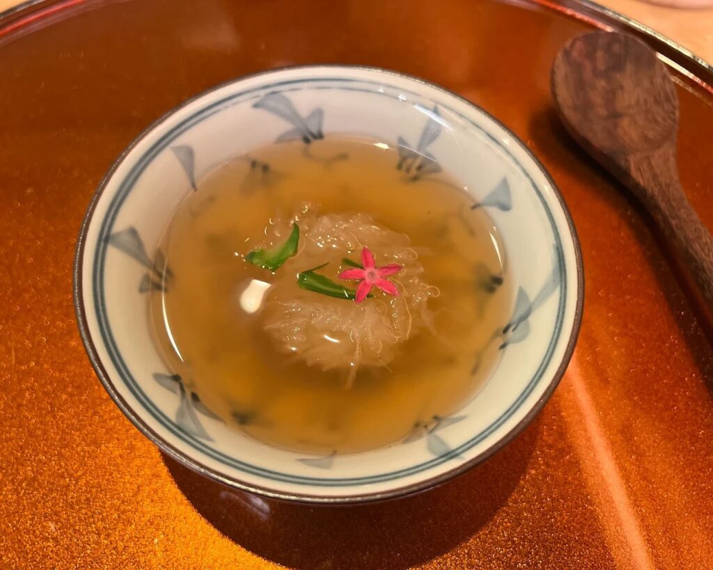 Clear, gently simmered soup served in traditional tableware, highlighting depth of flavour through delicate herbs and seasonal ingredients.