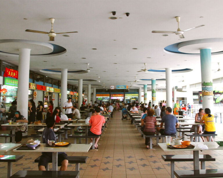 Visitors searching for available seating inside Tiong Bahru Market, capturing the lively atmosphere of the hawker centre during a busy meal hour.