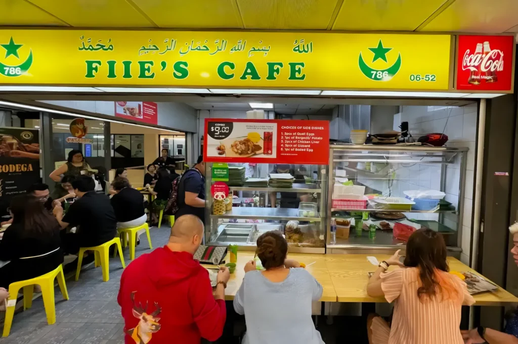 People dining at Fiie's Cafe, a vibrant eatery with a bright yellow sign. Customers sit at a counter, enjoying their meals in a lively atmosphere.