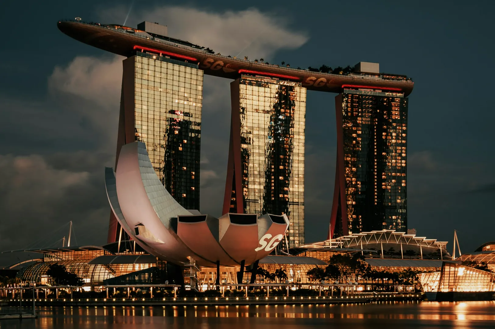 Night view of Marina Bay Sands in Singapore, with its distinctive boat-shaped skypark atop three towers and the ArtScience Museum in the foreground.