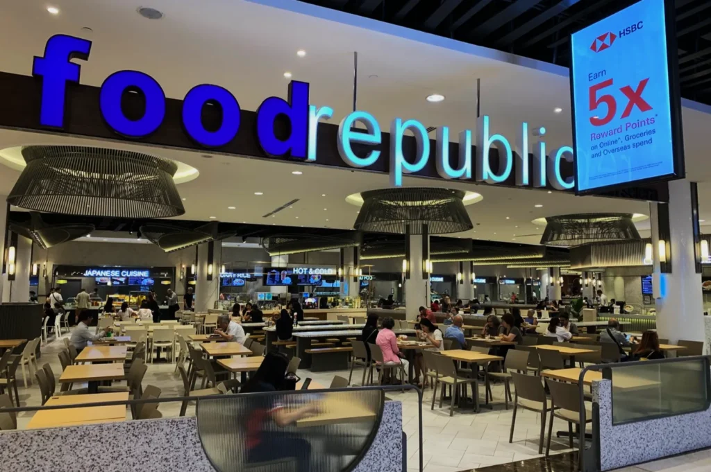 Food court named "food republic" with modern decor and ambient lighting. People are dining at scattered tables, creating a lively atmosphere.
