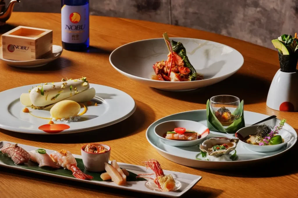 A lavish display of gourmet Japanese cuisine on a wooden table. Includes sushi, artful desserts, and beautifully plated seafood dishes, evoking elegance.