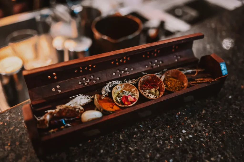 A wooden incense box on a countertop contains various spices and herbs in small compartments, emanating a warm, aromatic and inviting ambience.