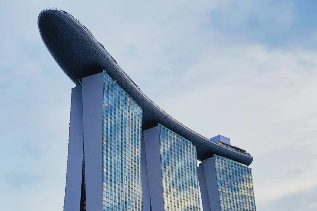 Futuristic building with three towers topped by a surfboard-like structure, under a blue sky. It exudes modernity and architectural innovation.