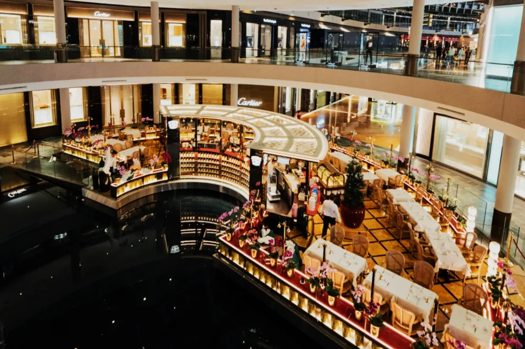 Luxurious shopping mall interior with elegant café and dining area. Tables are adorned with flowers, creating a sophisticated and inviting atmosphere.