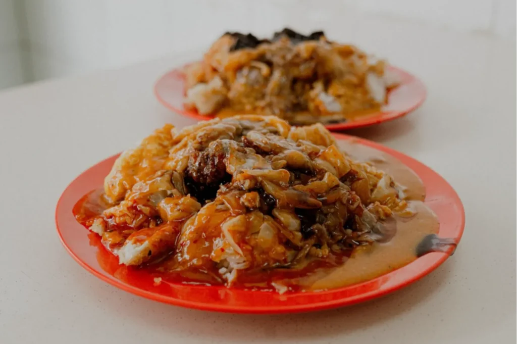 Two red plates filled with curry rice, soaked in rich, brown gravy with various toppings. The dish appears hearty and flavorful.
