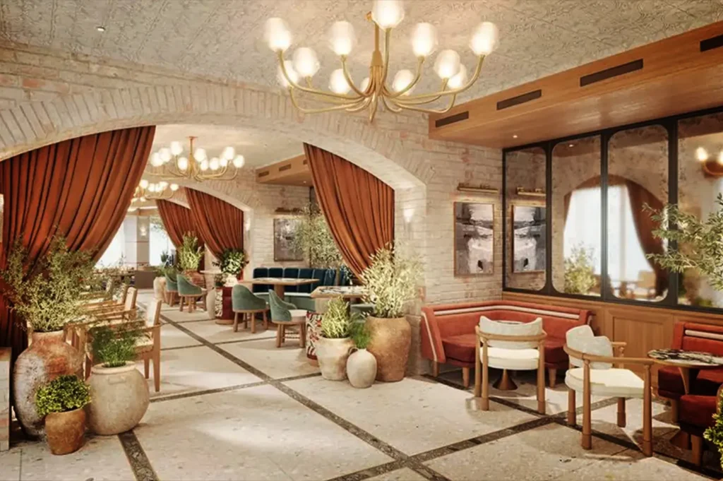 An eye-level, wide shot captures the elegant, Mediterranean-inspired interior of a upscale restaurant or lounge. The space features textured light-brick walls, a tiled floor with dark stone borders, and low, patterned ceilings adorned with multi-bulb gold chandeliers. On the left, a succession of large brick archways framed by heavy, draped terracotta curtains creates a corridor leading into deeper dining areas with green velvet booths. In the right foreground, an intimate seating alcove features curved reddish-brown banquettes, round marble-topped tables, and wooden accent chairs with plush white cushions, all beautifully accented by various green plants in large clay urns.